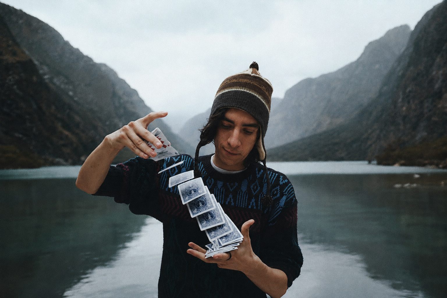 Juan Sebastian Casta performing a card flourish beside a mountain lake