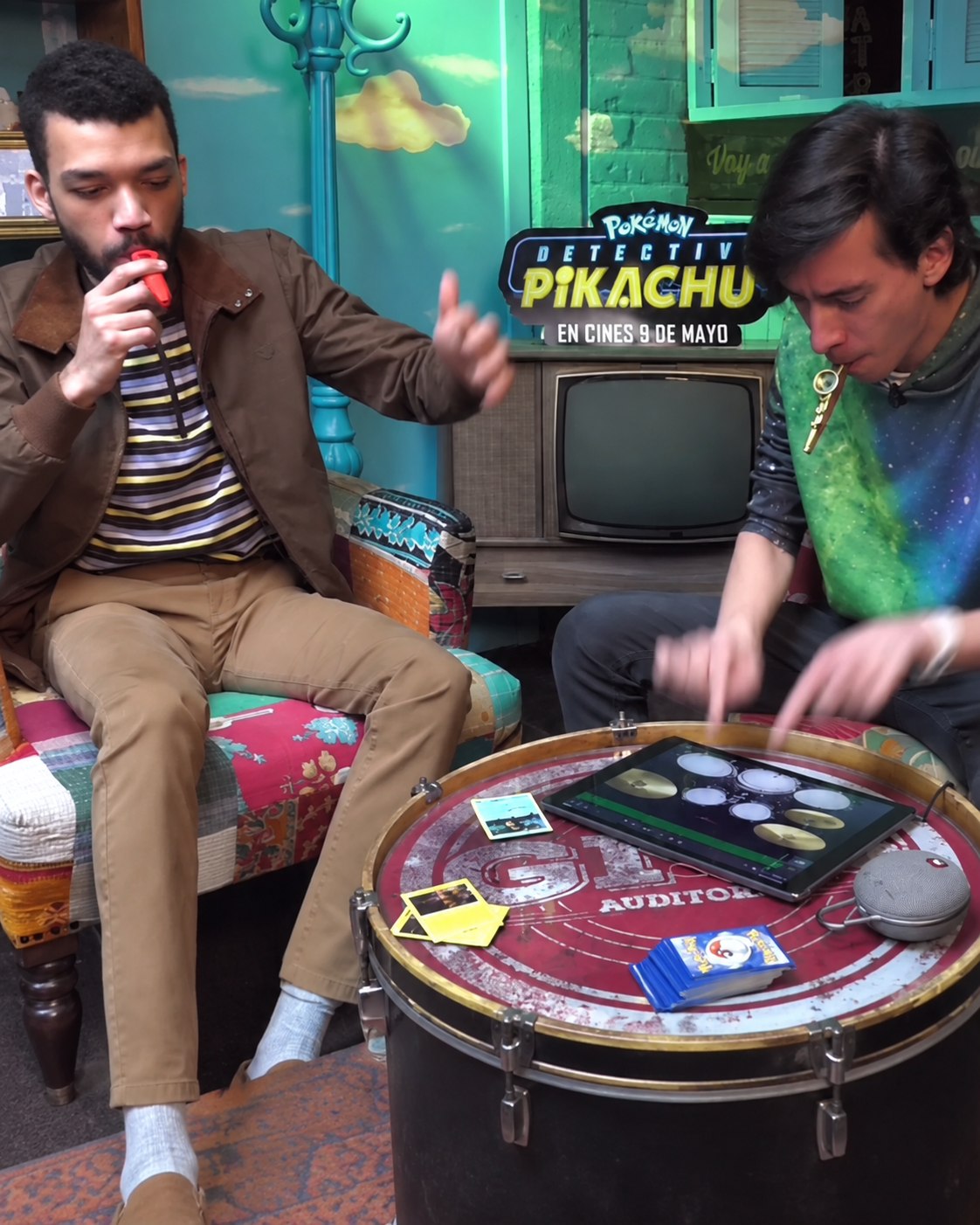 Justice Smith in a magic activation for Detective Pikachu, holding Pokémon cards during an interview.