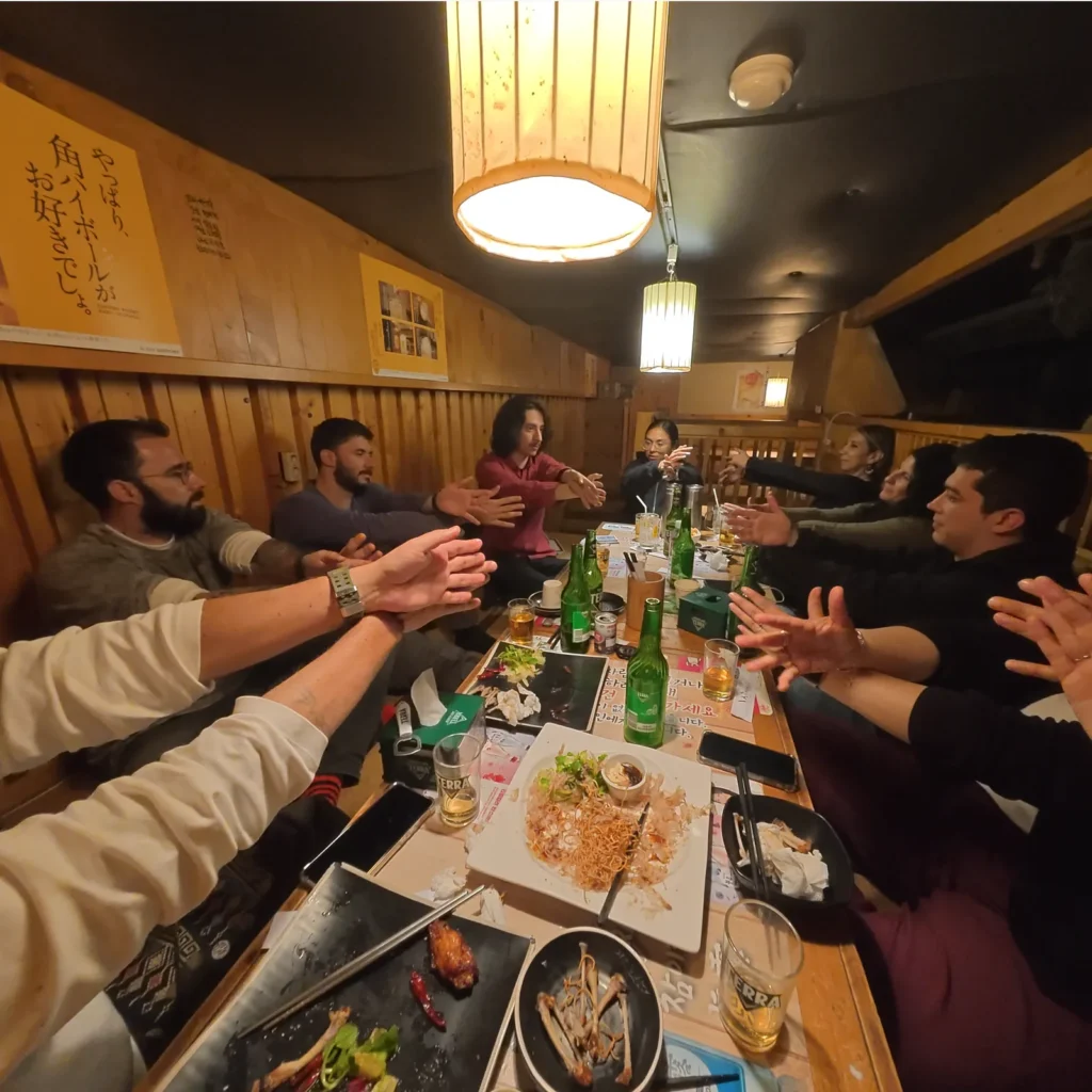 Participants following a crossed-arms magic activity around a restaurant table