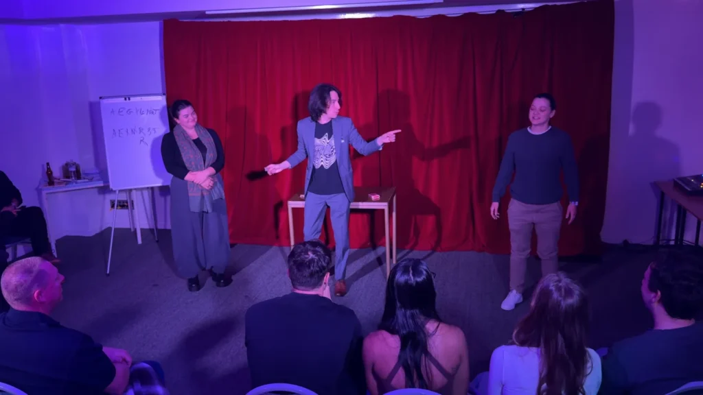 Sebastián performing with two volunteers in front of a seated audience.